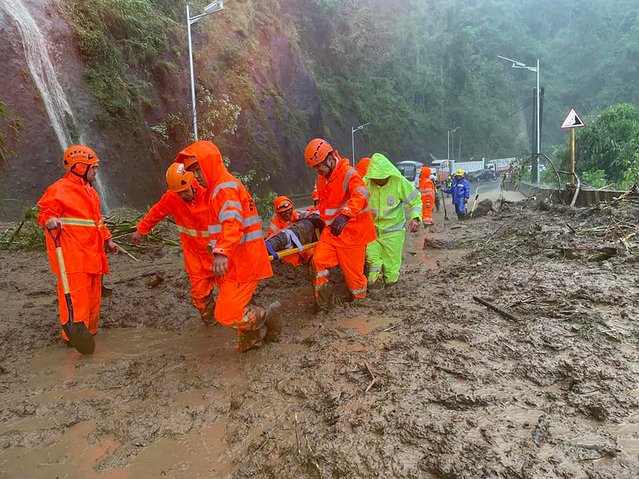 A handout photo taken on September 22, 2025 and received through the courtesy of Facebook page of Tuba Public Information Office on September 23, shows rescuers carrying an injured commuter on a stretcher after a landslide hit vehicles traversing a road at the height of Super Typhoon Ragasa in Tuba town, Benguet province, north of Manila. Ragasa had already toppled trees, tore the roofs off buildings and killed at least one person in a landslide while lashing the northern Philippines, where thousands sought shelter in schools and evacuation centres. (Photo by John Dimain/Tuba Public Information Office/AFP Photo) 