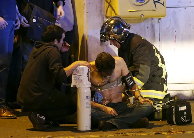 French fire brigade members aid an injured individual near the Bataclan concert hall following fatal shootings in Paris, France, November 13, 2015. (Photo by Christian Hartmann/Reuters)