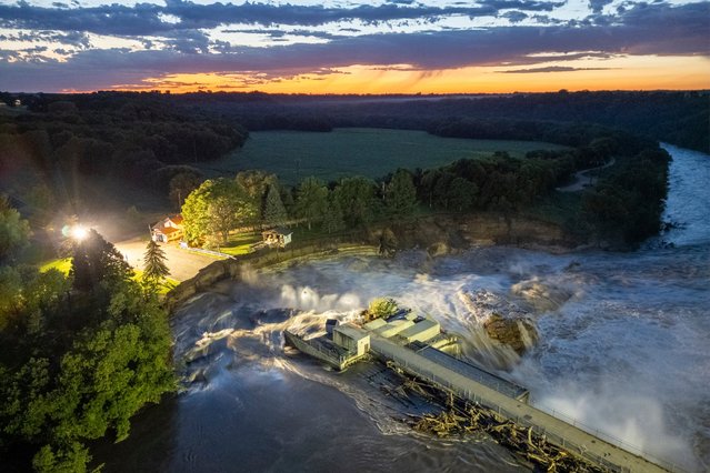 This long-exposure drone photo provided by AW Aerial shows a home as it teeters before partially collapsing into the Blue Earth River at the Rapidan Dam in Rapidan, Minn., Tuesday, June 25, 2024. (Photo by Andrew Weinzierl/AW Aerial via AP Photo)