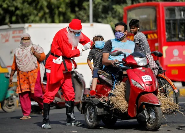 A man wearing a Santa Claus costume distributes free masks on an intersection, amidst the spread of the coronavirus disease (COVID-19), in Ahmedabad, India, December 18, 2020. (Photo by Amit Dave/Reuters)