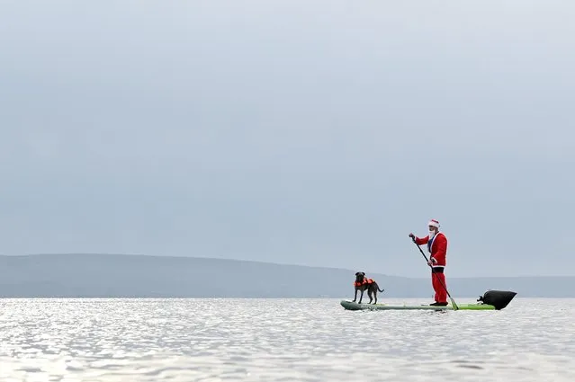 A man dressed as Santa Claus paddles on a board with his dog in Galway Bay in Galway, Ireland, December 22, 2020. (Photo by Clodagh Kilcoyne/Reuters)