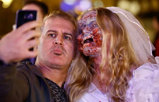 A man takes a selfie with a zombie bride during the so-called “Zombie walk” through the western German city of Essen on Halloween Day, October 31, 2016. (Photo by Wolfgang Rattay/Reuters)