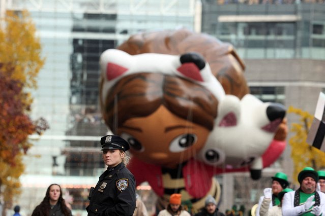 A police officer stands guard as the Gabby & Pandy Paws balloon flies during the Macy's Thanksgiving Day Parade 2025, in New York City, U.S., November 27, 2025. (Photo by Brendan McDermid/Reuters)