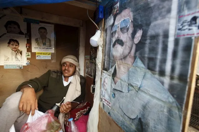 A street guard sits in his kiosk next to a poster of Yemen's former president Ali Abdullah Saleh at the old quarter of Yemen's capital Sanaa November 27, 2015. (Photo by Khaled Abdullah/Reuters)