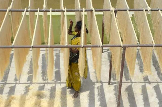 An Indian worker arranges strands of vermicelli noodles to dry at a factory during on the outskirts of Chennai on June 1, 2018. Sheer khurma, or sheer khorma, is a sweet dish prepared with vermicelli noodles and eaten during the during the Islamic holy month of Ramadan. (Photo by Arun Sankar/AFP Photo)