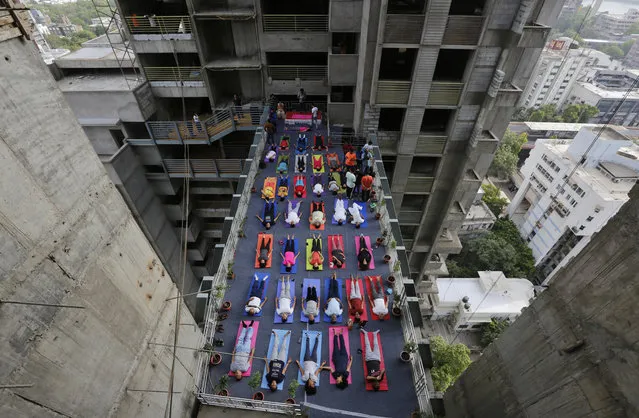 In this Thursday, June 21, 2018, file photo, Indians performs yoga on a walk-way between two towers of an under construction high rise residential building as they mark International Yoga Day in Ahmadabad, India. Yoga enthusiasts across the world Thursday took part in mass yoga events to mark International Yoga Day. (Photo by Ajit Solanki/AP Photo)
