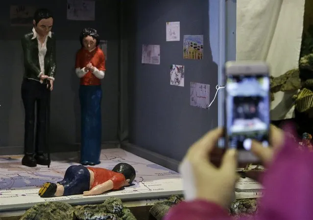 A woman takes pictures of a nativity scene in which Jesus is represented by the lifeless body of three-year-old Syrian refugee Aylan Kurdi, who made global headlines after he drowned in the Mediterranean Sea as his family attempted to enter Europe from Turkey, in the San Anton church in Madrid, Spain, December 15, 2015. (Photo by Andrea Comas/Reuters)