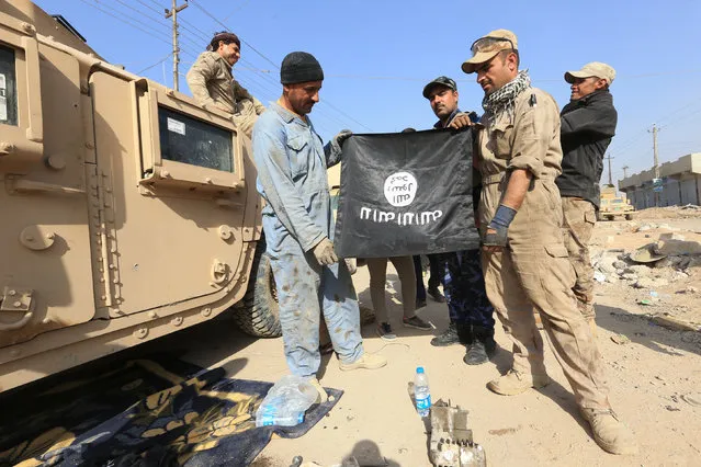 Iraqi soldiers pose with the Islamic State flag along a street in the Intisar district of eastern Mosul, Iraq, November 14, 2016, after capturing the same area from this district from the Islamic State on November 3. (Photo by Air Jalal/Reuters)