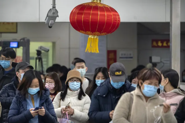 Commuters wearing face masks to protect against the spread of the coronavirus walk through turnstiles in a subway station during the evening rush hour in Beijing, Friday, February 26, 2021. China has been regularly reporting no locally transmitted cases of COVID-19 as it works to maintain control of the pandemic within its borders. (Photo by Mark Schiefelbein/AP Photo)