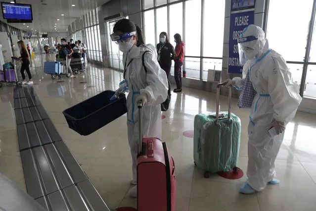 Foreign passengers wearing protective suits push their bags as they prepare for their flight to China at Manila's International Airport, Philippines, Monday, January 18, 2021. Coronavirus infections in the Philippines have surged past 500,000 in a new bleak milestone with the government facing criticisms for failing to immediately launch a vaccination program amid a global scramble for COVID-19 vaccines. (Photo by Aaron Favila/AP Photo)