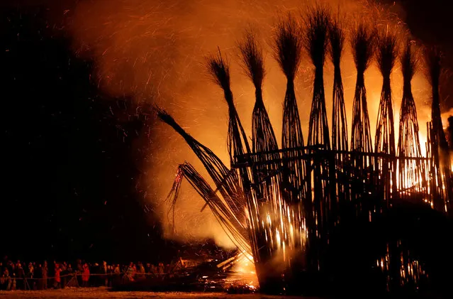 Spectators look at the burning installation during a performance devoted to Maslenitsa, or Pancake Week, a pagan holiday marking the end of winter, in the village of Nikola-Lenivets, Kaluga region, Russia, February 17, 2018. (Photo by Maxim Shemetov/Reuters)