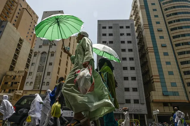 Muslim pilgrims use umbrellas to protect themselves from the sun as they walk in the holy city of Mecca on June 23, 2023. (Photo by Sajjad Hussain/AFP Photo)