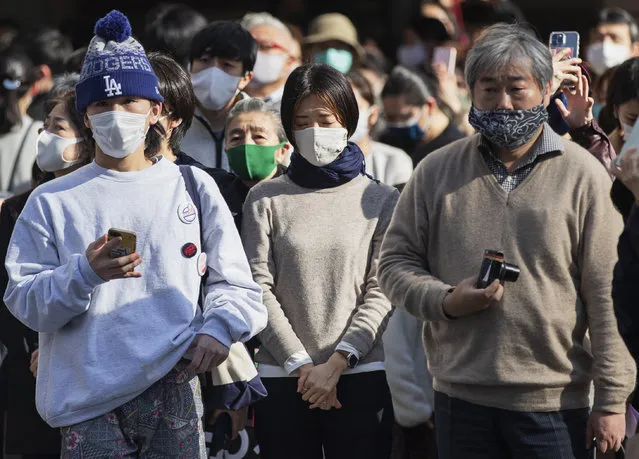 One of the bystanders waiting at a traffic intersection closes her eyes when an annual tribute started at 2:46 p.m. for the victims of a 2011 disaster in Tokyo Thursday, March 11, 2021. Japan is marking the 10th anniversary Thursday of the earthquake, tsunami and nuclear disaster that hit the northeastern region. (Photo by Hiro Komae/AP Photo)