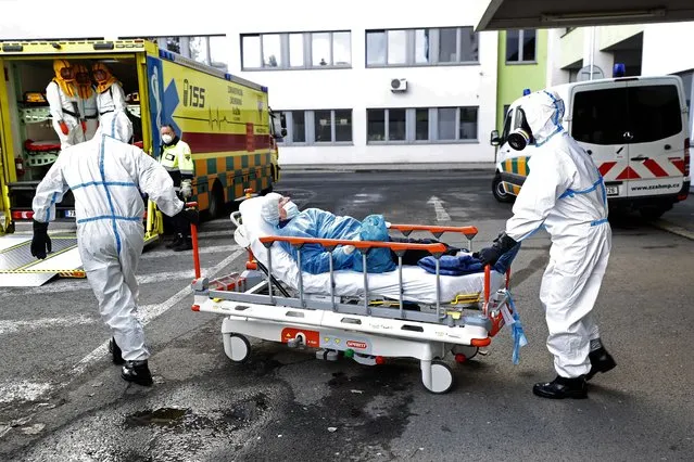 Health care workers assist COVID-19 patient during a transport from a overrun hospital in Ceska Lipa, Czech Republic, Thursday, March 18, 2021. Some patients are being moved from over-run hospitals, as coronavirus puts pressure on health care services. (Photo by Petr David Josek/AP Photo)