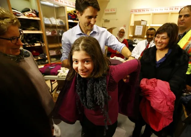 Canada's Prime Minister Justin Trudeau helps a young Syrian refugee try on a winter coat after she arrived with her family from Beirut at the Toronto Pearson International Airport in Mississauga, Ontario, Canada December 11, 2015. After months of promises and weeks of preparation, the first Canadian government planeload of Syrian refugees landed in Toronto on Thursday, aboard a military aircraft met by Prime Minister Justin Trudeau. (Photo by Mark Blinch/Reuters)