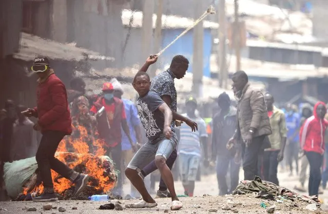 Supporters of Kenya's opposition leader Raila Odinga of the Azimio La Umoja (Declaration of Unity) One Kenya Alliance, hurl stones at riot police officers during an anti-government protest against the imposition of tax hikes by the government, in Mathare settlement in Nairobi, Kenya on July 19, 2023. (Photo by John Muchucha/Reuters)