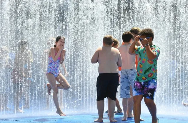 Children play in the fountain on the South Bank in London, UK on Sunday July 15, 2018. (Photo by John Stillwell/PA Wire)