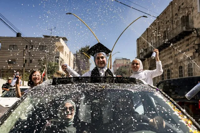 A Palestinian student celebrates in a car as others spray foam around her after the Palestinian Education Ministry announced the results for high school diploma examinations, in the city of Hebron in the occupied West Bank on July 20, 2023. (Photo by Hazem Bader/AFP Photo)