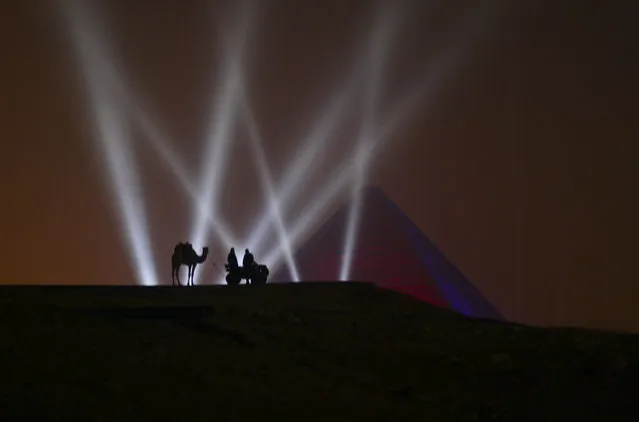 Two Egyptian men and a camel stand on a hill overlooking one of the Giza Pyramids during a New Year's Eve fireworks display near Cairo, Egypt at midnight on Friday, January 1, 2016. (Photo by Maya Alleruzzo/AP Photo)