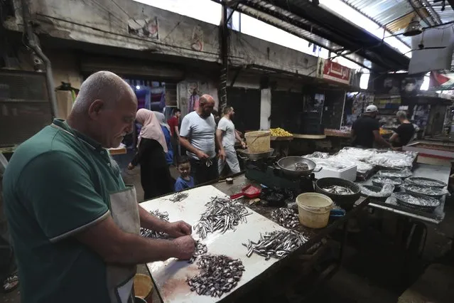 A fish vendor cleans fish in a market at Ein el-Hilweh Palestinian refugee camp, in the southern port city of Sidon, Lebanon, Tuesday, June 20, 2023. (Photo by Mohammed Zaatari/AP Photo)