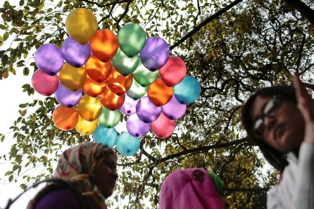 Bangladeshi girls walk near balloons floating in air as they celebrate the arrival of spring on the first day of Falgoon at the Dhaka University campus in Dhaka, Bangladesh, Friday, February 13, 2015. (Photo by A. M. Ahad/AP Photo)