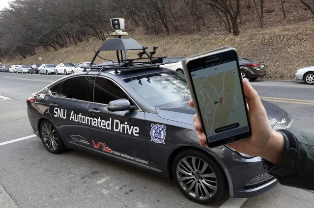 A researcher fromm the Intelligent Vehicle IT Research Center at Seoul National University shows the smartphone application for the driverless car called Snuber with a fixture on its roof with devices that scan road conditions at Seoul National University's campus in Seoul, South Korea, Tuesday, January 5, 2016. The South Korean university is testing the sedan that can pick up and transport passengers without a human driver, giving a glimpse into the future of autonomous public transport. (Photo by Lee Jin-man/AP Photo)