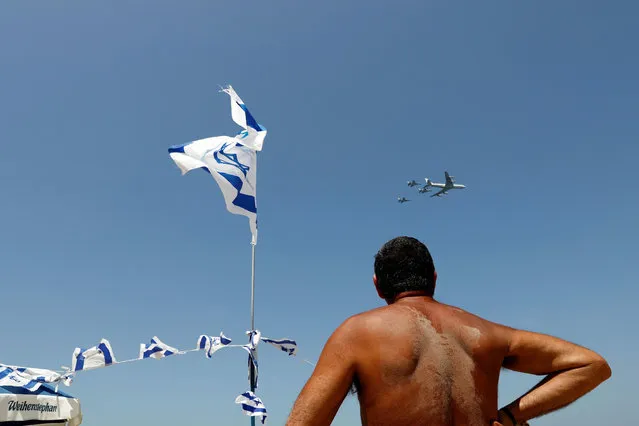 A man watches as Israeli Air Force planes fly in formation over the Mediterranean Sea during an aerial show as part of the celebrations for Israel's Independence Day marking the 73rd anniversary of the creation of the state, at a beach in Tel Aviv, Israel on April 15, 2021. (Photo by Corinna Kern/Reuters)