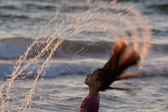 A Palestinian girl plays with water while enjoying a day at the beach in the Mediterranean Sea during a heat wave in Gaza City, Friday, July 21, 2023. (Photo by Adel Hana/AP Photo)