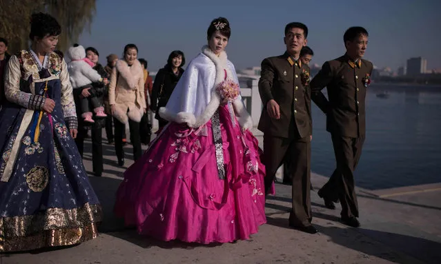 A bride and groom walk with relatives and friends as they prepare to pose for their wedding photos by the Taedong river in Pyongyang on November 25, 2016. (Photo by Ed Jones/AFP Photo)