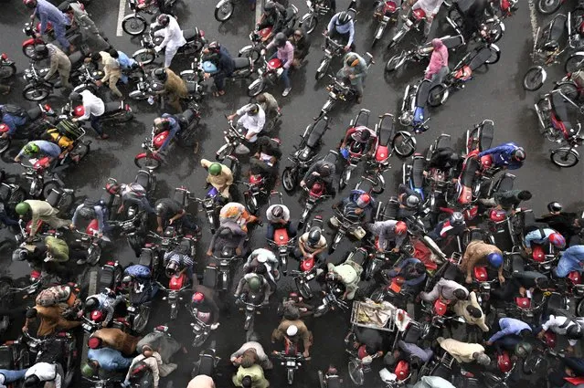 Commuters wait in traffic after other commuters blocked a road while sheltering under a bridge during a heavy rainfall in Islamabad on August 17, 2023. (Photo by Farooq Naeem/AFP Photo)