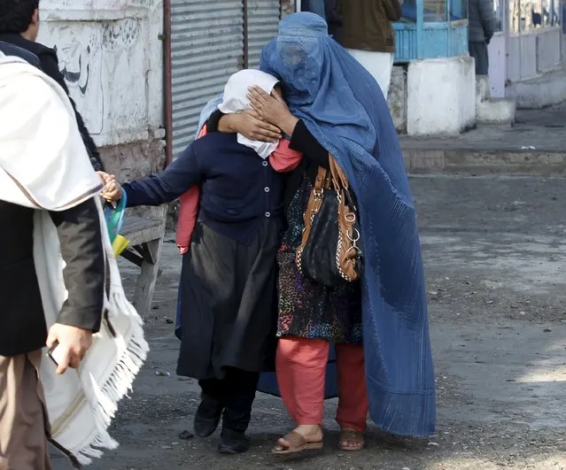 A woman holds her daughter's head as they walk away after a blast near the Pakistani consulate in Jalalabad, Afghanistan January 13, 2016. (Photo by Reuters/Parwiz)