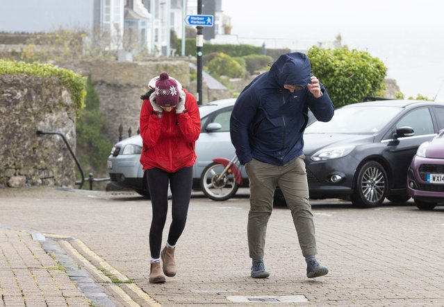 Members of the public battling the wind on The Paragon on May 20, 2021 in Tenby, Wales. The Met Office have issued a Yellow Beware warning with winds expected to reach up to 68mph, which could bring disruption to parts of south and mid Wales on Thursday and Friday. (Photo by Huw Fairclough/Getty Images)