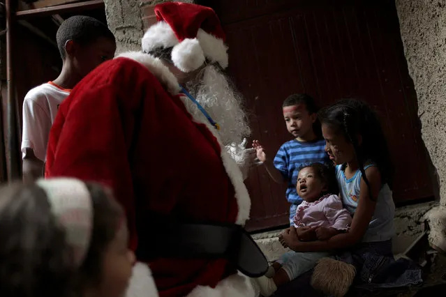 Santa Claus greets a children during a visit to residents of the slum of Petare in Caracas, Venezuela, December 11, 2016. (Photo by Ueslei Marcelino/Reuters)