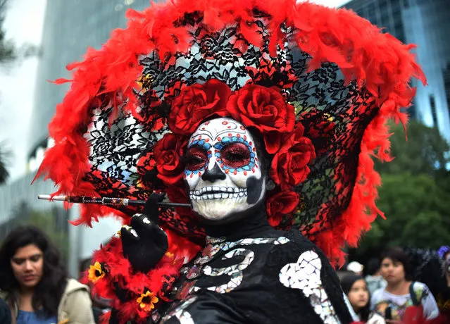 People fancy dressed as “Catrina” take part in the “Catrinas Parade” along Reforma Avenue, in Mexico City on October 21, 2018. Mexicans get ready to celebrate the Day of the Dead highlighting the character of La Catrina which was created by cartoonist Jose Guadalupe Posada, famous for his drawings of typical local, folkloric scenes, socio- political criticism and for his illustrations of “skeletons” or skulls, including La Catrina. (Photo by Rodrigo Arangua/AFP Photo)