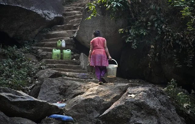Plastic cans filled with water are kept on the steps as an Indian woman carries buckets of washed clothes and drinking water up a hill on World Water Day in Gauhati, India, Sunday, March 22, 2015. (Photo by Anupam Nath/AP Photo)
