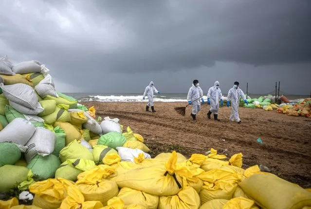 Sri Lankan navy soldiers walk on the beach looking for plastic debris washed ashore from fire damaged container ship MV X-Press Pearl at Kapungoda, on the outskirts of Colombo, Sri Lanka. Monday, June 14, 2021. (Photo by Eranga Jayawardena/AP Photo)