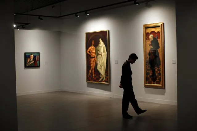 A security guard is silhouetted in front of (L-R) “Portrait of the collector Alexander Korovin” (L), “Self Portraits” (Harlequin and Piero) and "Violinist”, by Russian-born artists Boris Grigoriev, Vasily Shukhaev and Alexander Yakovlev respectively, during an international press tour of the Malaga branch of the State Museum of Russian Art of St Petersburg, a day before its inauguration in Malaga, southern Spain March 24, 2015. (Photo by Jon Nazca/Reuters)