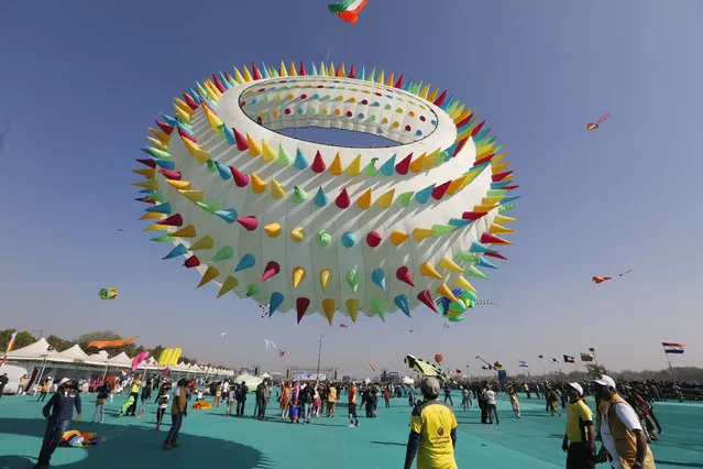 Indians watch a huge kite fly during International kite festival in Ahmadabad, India, Sunday, January 6, 2019. Kite flyers from various countries and across India are participating in the festival that is annually held on the Sabarmati riverfront here. (Photo by Ajit Solanki/AP Photo)