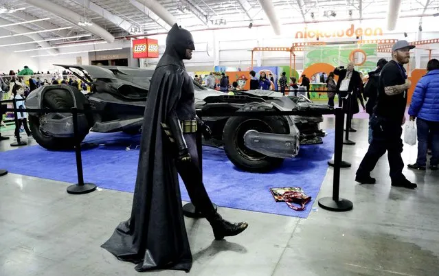 A costumed Batman walks past the Batmobile at Toy Fair, Sunday, February 14, 2016, in New York. The Batmobile was used in the filming of the upcoming movie: “Batman v Superman: Dawn of Justice”. (Photo by Mark Lennihan/AP Photo)
