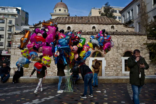 Balloon vendors stand in a square waiting for customers in Athens, Greece, Sunday, January 8, 2017. (Photo by Muhammed Muheisen/AP Photo)