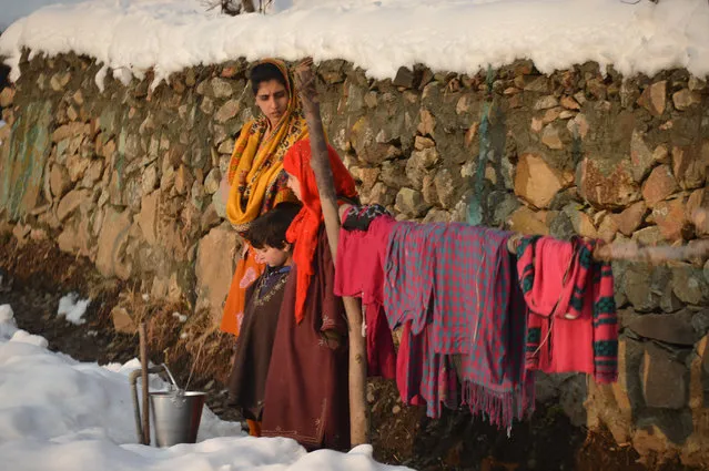 A Kashmiri woman waits as she fill an iron bucket with water in a neighbourhood on the outskirts of Srinagar following the season's first snowfall in Kashmir on January 11, 2017. The tourism industry is hoping that 2017 will herald a renewal of tourists to the scenic region after last year's civil unrest drove both domestic and foreign tourists out of the valley. More than 90 civilians have been killed and thousands injured during the latest protests against Indian rule, sparked by the killing on July 8, 2016, of a popular rebel leader of Hizbul Mujahideen during a gunfight with Indian soldiers. Kashmir has been divided between India and Pakistan since their independence from British rule in 1947, and both claim the territory. (Photo by Tauseef Mustafa/AFP Photo)