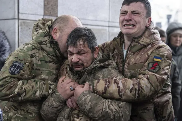 Ukrainian servicemen cry near the coffin of their comrade Andrii Trachuk during his funeral service on Independence square in Kyiv, Ukraine, Friday, December 15, 2023. Trachuk was a veteran of Revolution of Dignity and was killed by Russian forces on Dec. 9, 2023 near Kherson. (Photo by Evgeniy Maloletka/AP Photo)