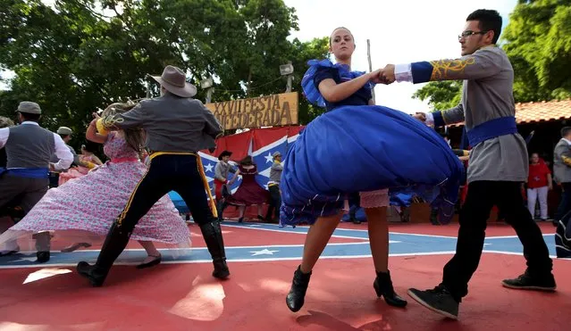 Descendants of American Southerners wearing Confederate-era dresses and uniforms dance during a party to celebrate the 150th anniversary of the end of the American Civil War in Santa Barbara D'Oeste, Brazil, April 26, 2015. The U.S. Civil War ended 150 years ago, but once a year, deep in the sugar cane fields of southern Brazil, the Confederate battle flag rises again. (Photo by Paulo Whitaker/Reuters)