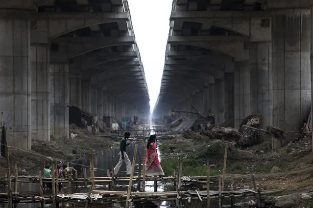 Indian residents walk across a makeshift bridge over a sewage canal under the Digha Bridge link road in Danapur, in the Indian state of Bihar on April 7, 2019. (Photo by Xavier Galiana/AFP Photo)