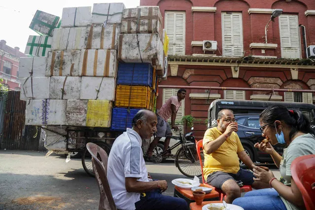 People eat a meal early morning on a street in Kolkata, India, Saturday, October 23, 2021. (Photo by Bikas Das/AP Photo)