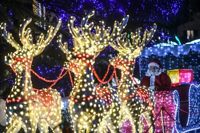 A performer dressed as Santa Claus with sleigh and reindeers is pictured among luminous choreographies and handmade sculptures made of over half a million lights at the Christmas Lights art installation in Leggiuno, on the shores of Lake Maggiore, on December 13, 2022. (Photo by Piero Cruciatti/AFP Photo)
