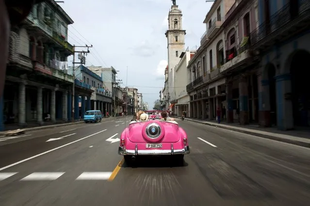 Tourists ride in a vintage car in Havana, March 19, 2016. (Photo by Alexandre Meneghini/Reuters)