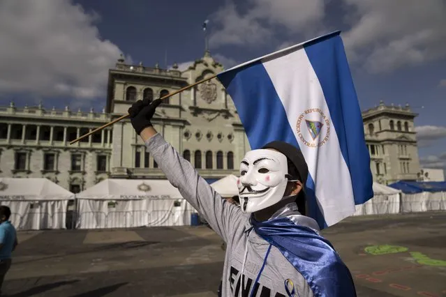 A Nicaraguan citizen protests against President Daniel Ortega at the Constitution Square in Guatemala City, Sunday, November 7, 2021. Ortega seeks a fourth consecutive term against a field of little-known candidates while those who could have given him a real challenge sit in jail. (Photo by Moises Castillo/AP Photo)