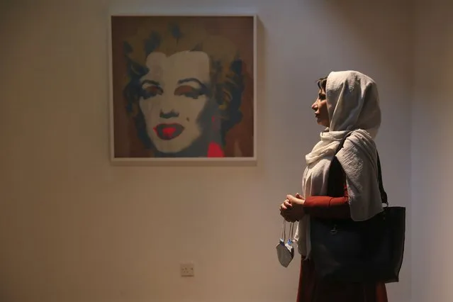 Fatemeh Rezaei, a retired teacher, stands next to Marilyn Monroe portrait by American artist Andy Warhol at Tehran Museum of Contemporary Art in Tehran, Iran on October 19, 2021. Iranians are flocking to Tehran's contemporary art museum to marvel at American pop artist Andy Warhol’s iconic work. (Photo by Vahid Salemi/AP Photo)