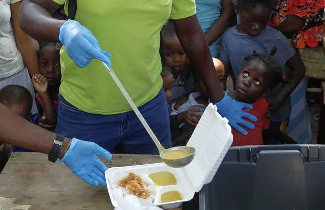 A server ladles soup into a container as children line up to receive food at a shelter for families displaced by gang violence, in Port-au-Prince, Haiti, Thursday, March 14, 2024. (Photo by Odelyn Joseph/AP Photo)